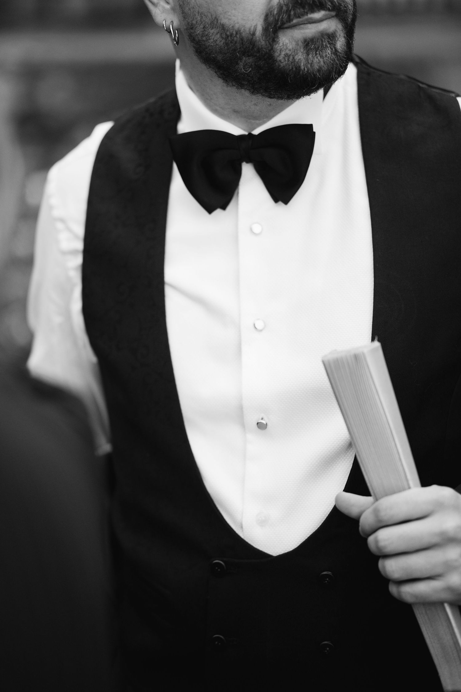 A black and white photo shows someone wearing a formal tuxedo with white shirt and black bow tie.