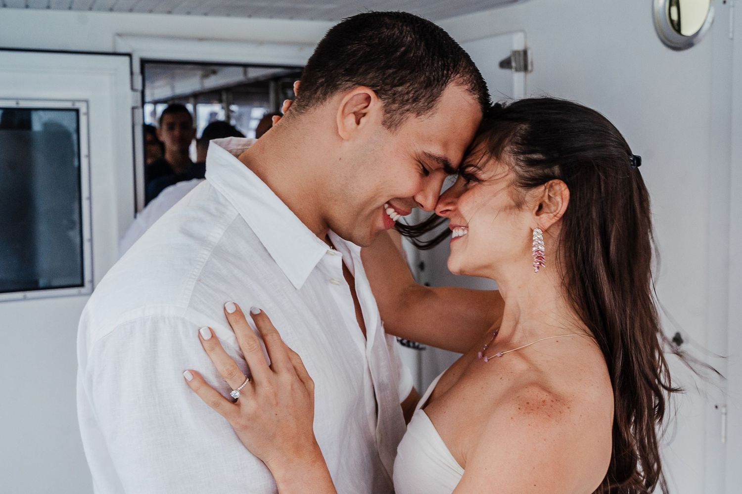 A couple shares intimate moments in a bright indoor setting with white walls.