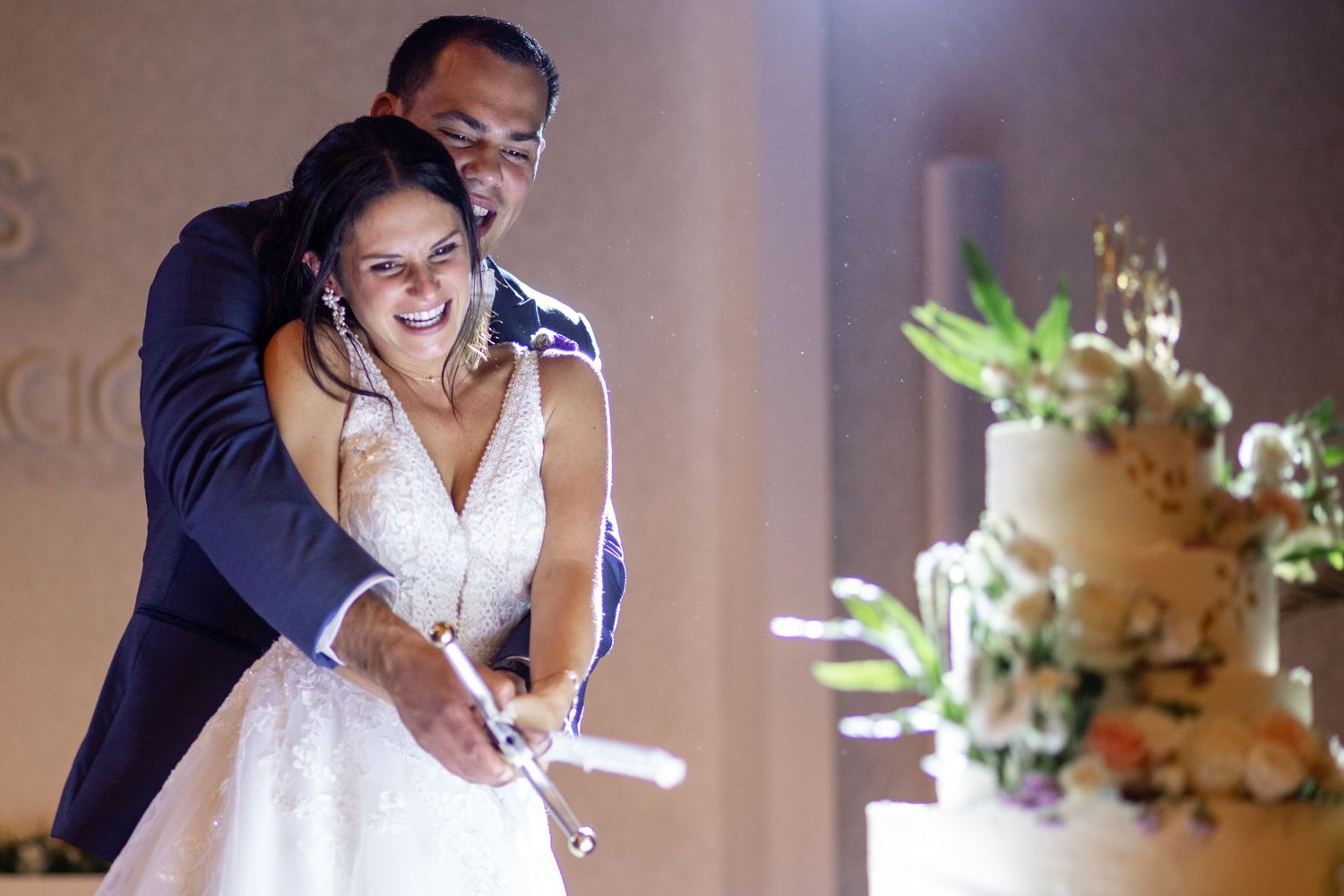 A couple shares a romantic dance moment at their wedding reception in a softly lit ballroom.