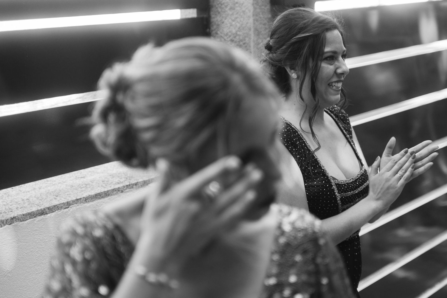 Black and white photo showing multiple people in motion with fluorescent lights overhead creating dramatic lighting.