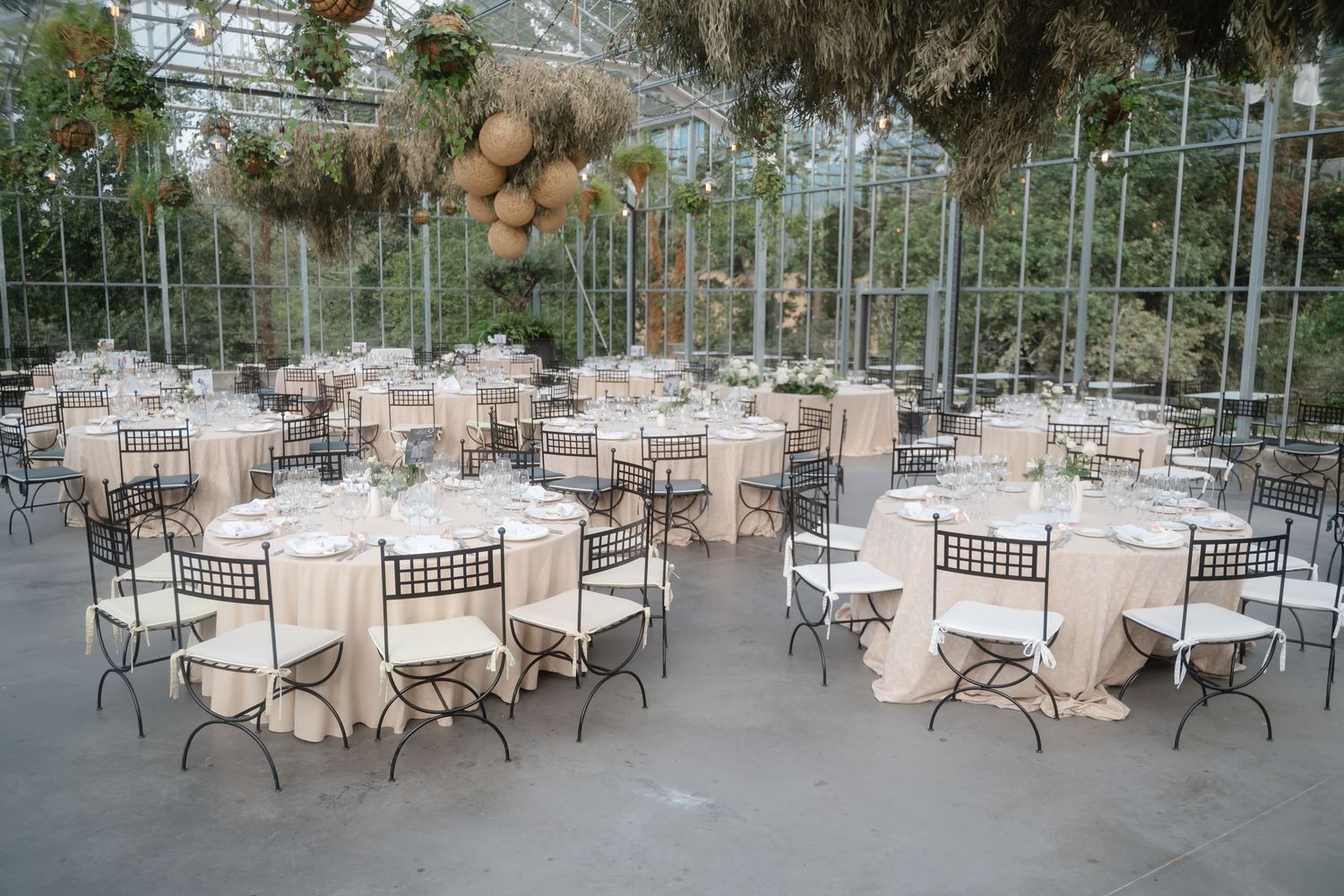 An elegant outdoor wedding reception setup with white tablecloths and chairs arranged under a covered patio area.