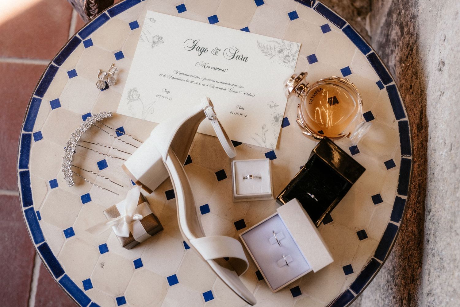 Wedding details including perfume bottles, invitations, and decorative items arranged on a polka dot plate.