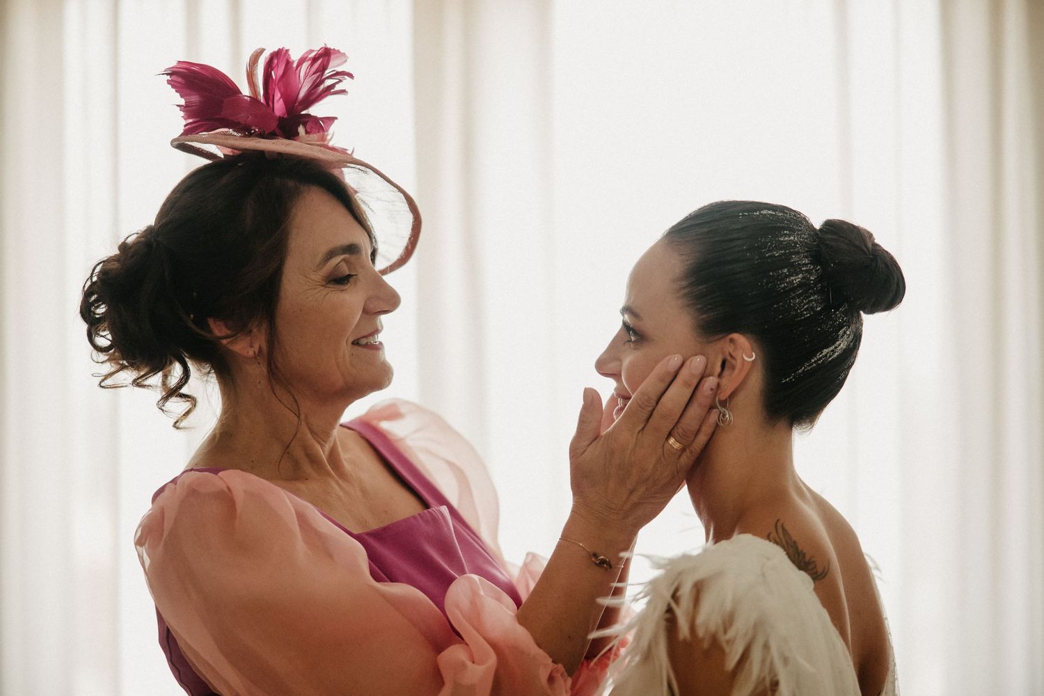 Wedding party members in burgundy dresses share joyful moments while getting ready in a bright room.
