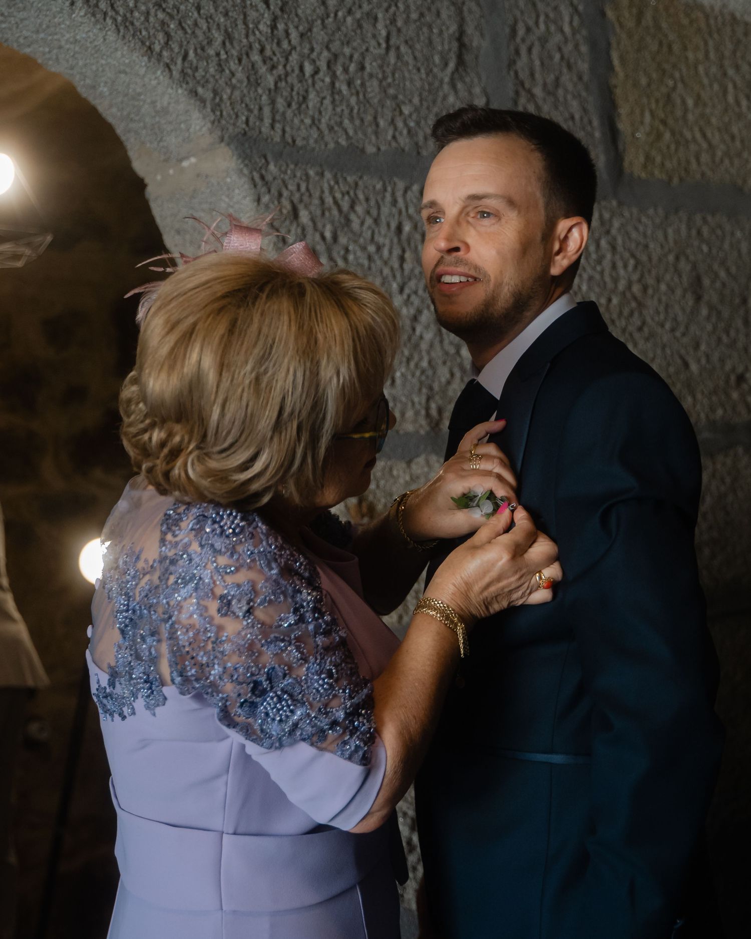 A couple dancing together in an intimate moment on a dimly lit dance floor with stone walls in the background.