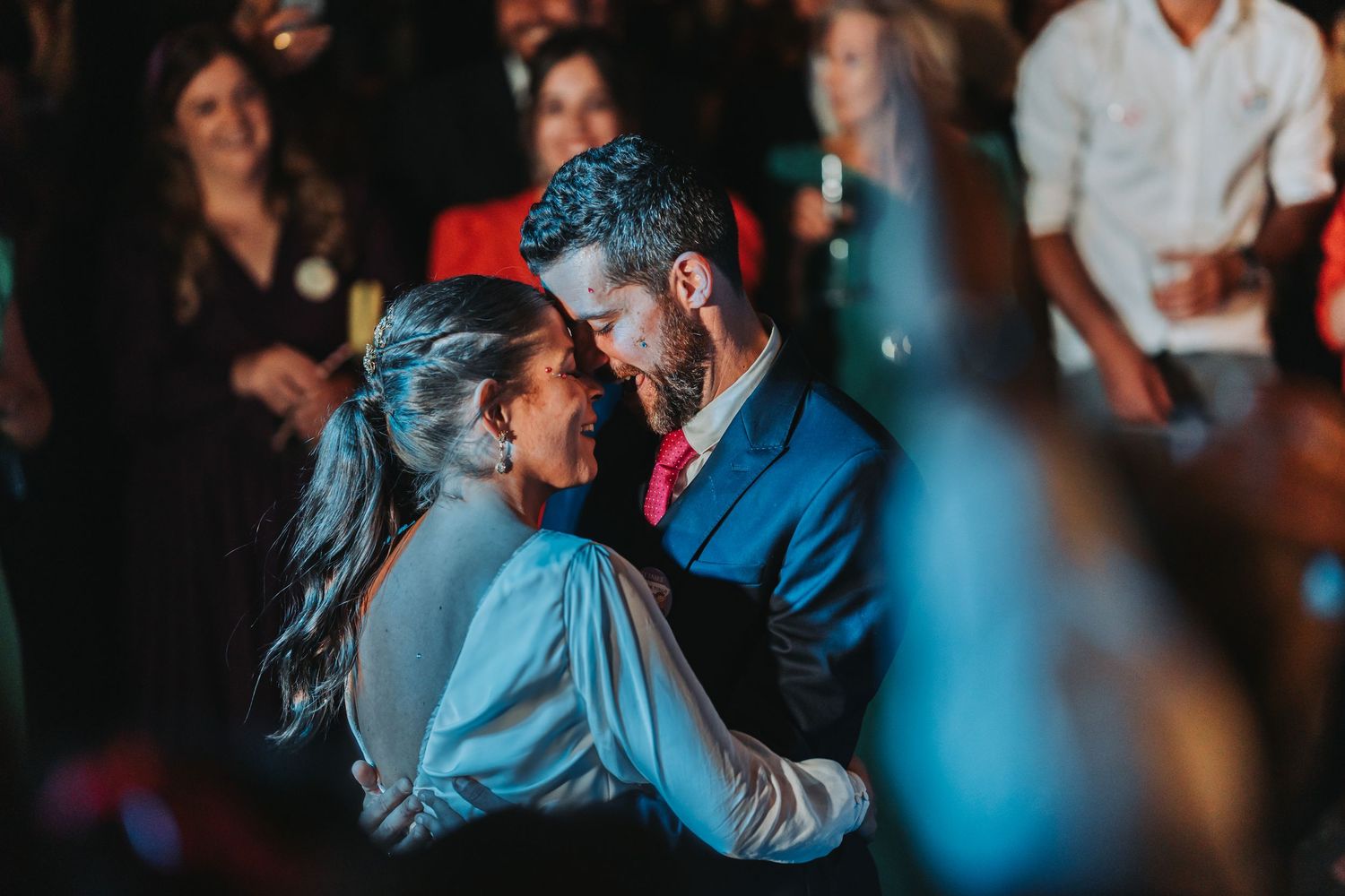 A couple dances together in an intimate embrace during a romantic evening event with blue lighting.