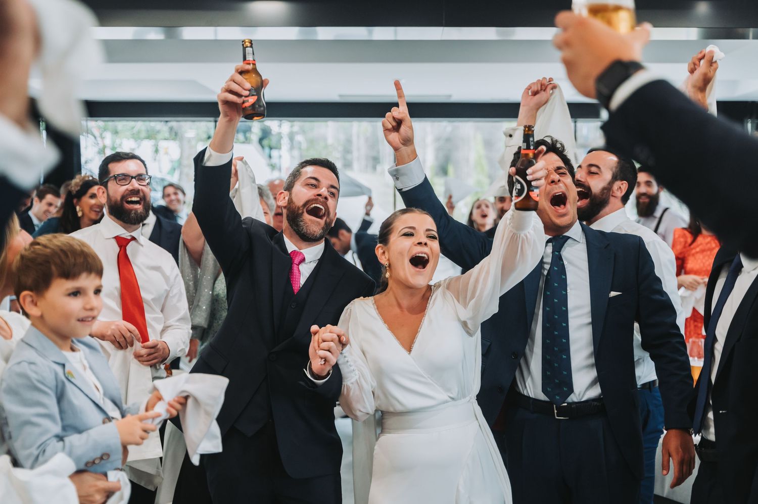 Wedding guests cheer and raise their hands in celebration during a joyous reception party moment.
