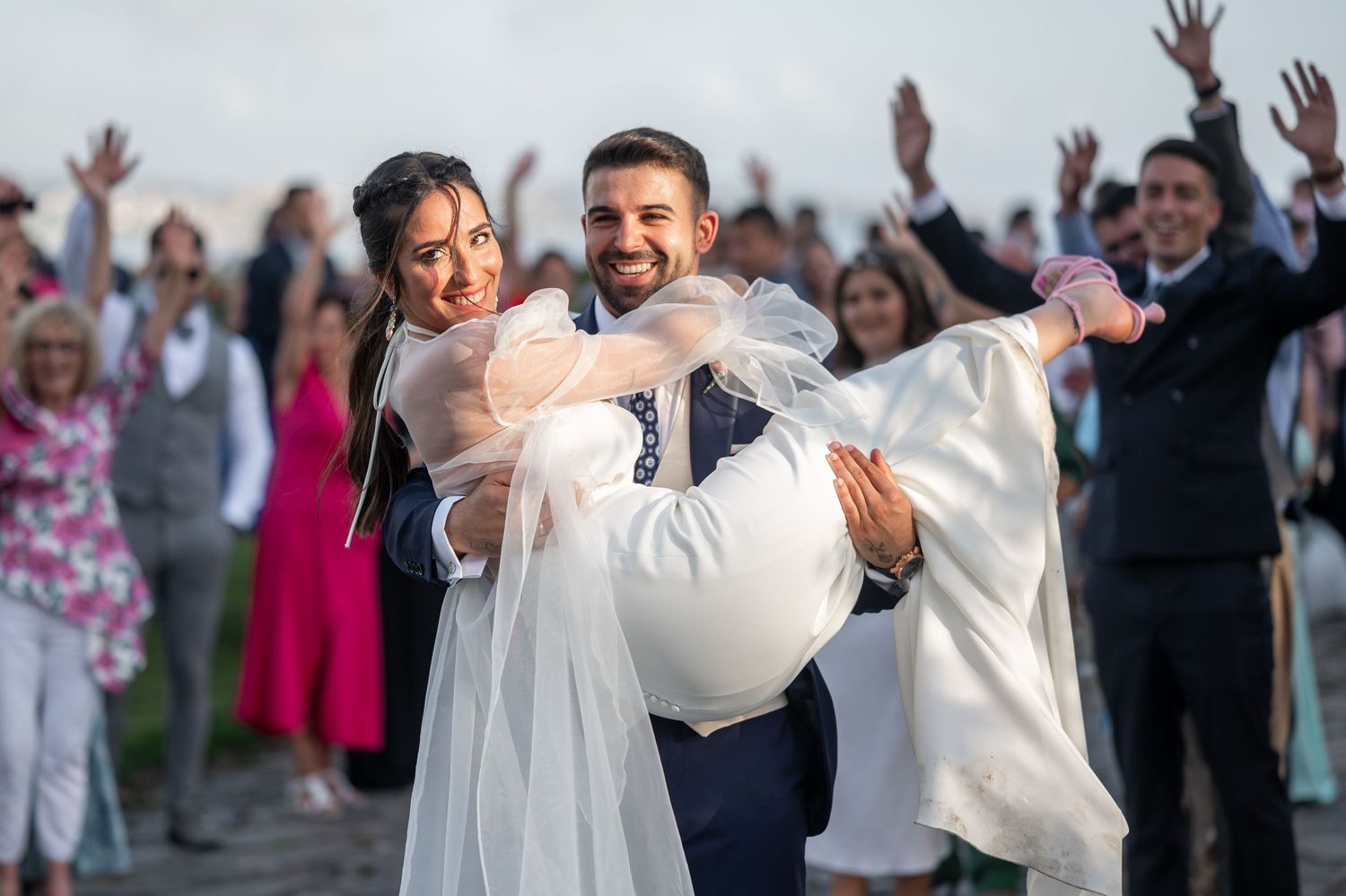 A joyful couple celebrates their wedding day as guests cheer in the background.