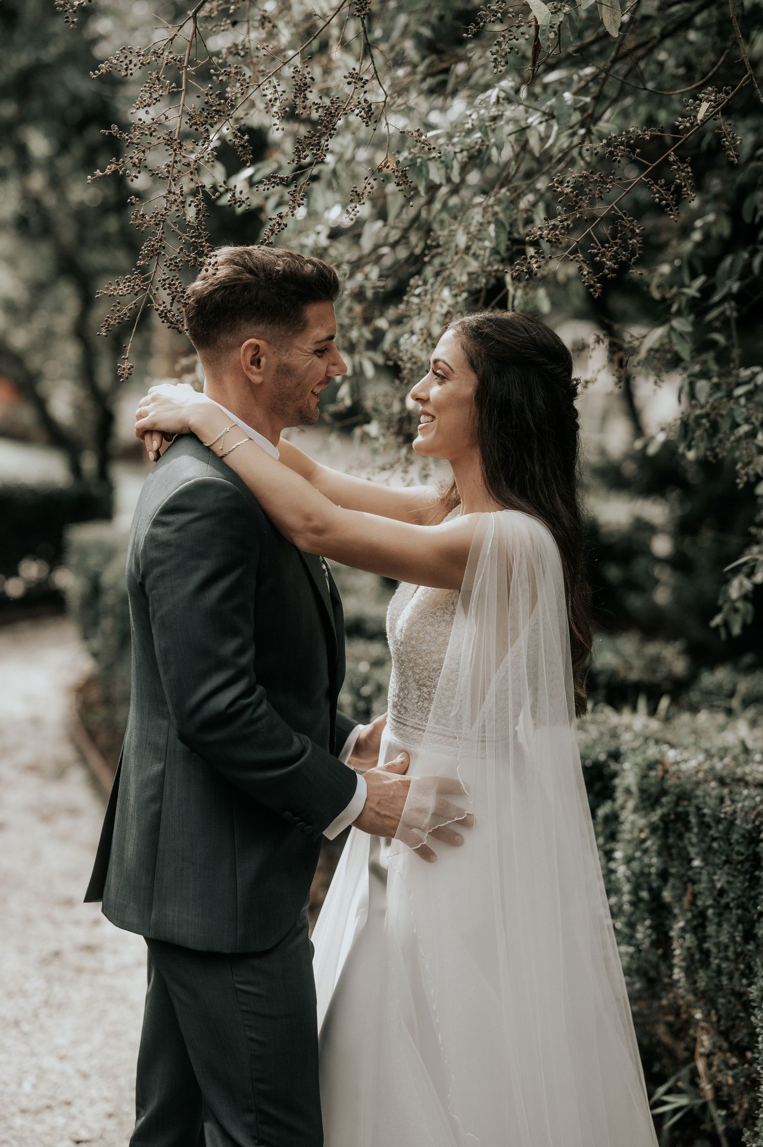 A romantic wedding moment captured in a garden setting with soft lighting and flowing veil details.