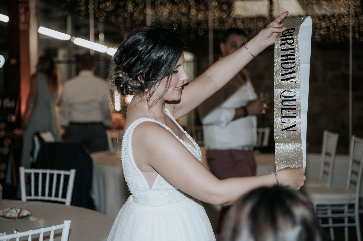 A couple shares a romantic dance together at an elegant wedding reception with white chairs and decor.
