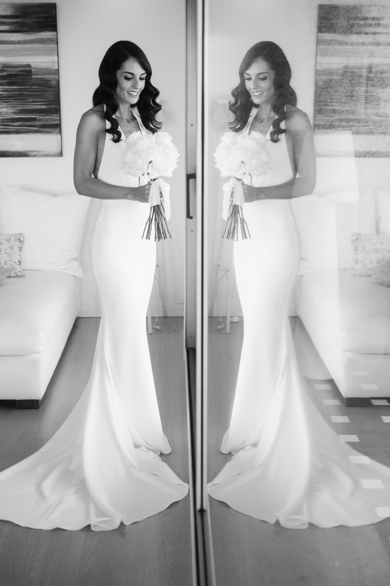Classic white bridal gown with sleek silhouette and bouquet captured in black and white through mirrored reflections.
