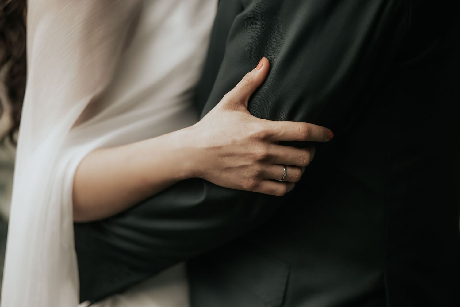 A couple holds hands intimately in a black and white artistic photo series.