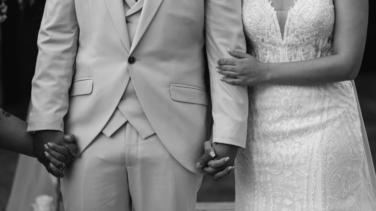 Wedding couple in elegant attire with bride in white lace dress and groom in light suit.