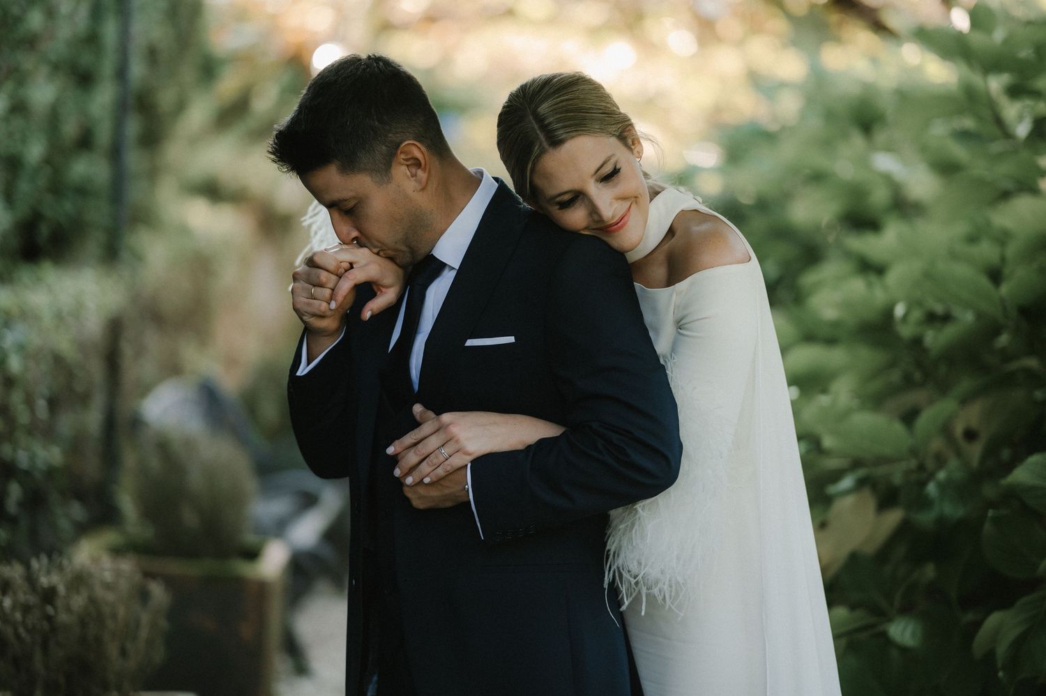Candid wedding couple moment in garden setting with soft natural lighting.