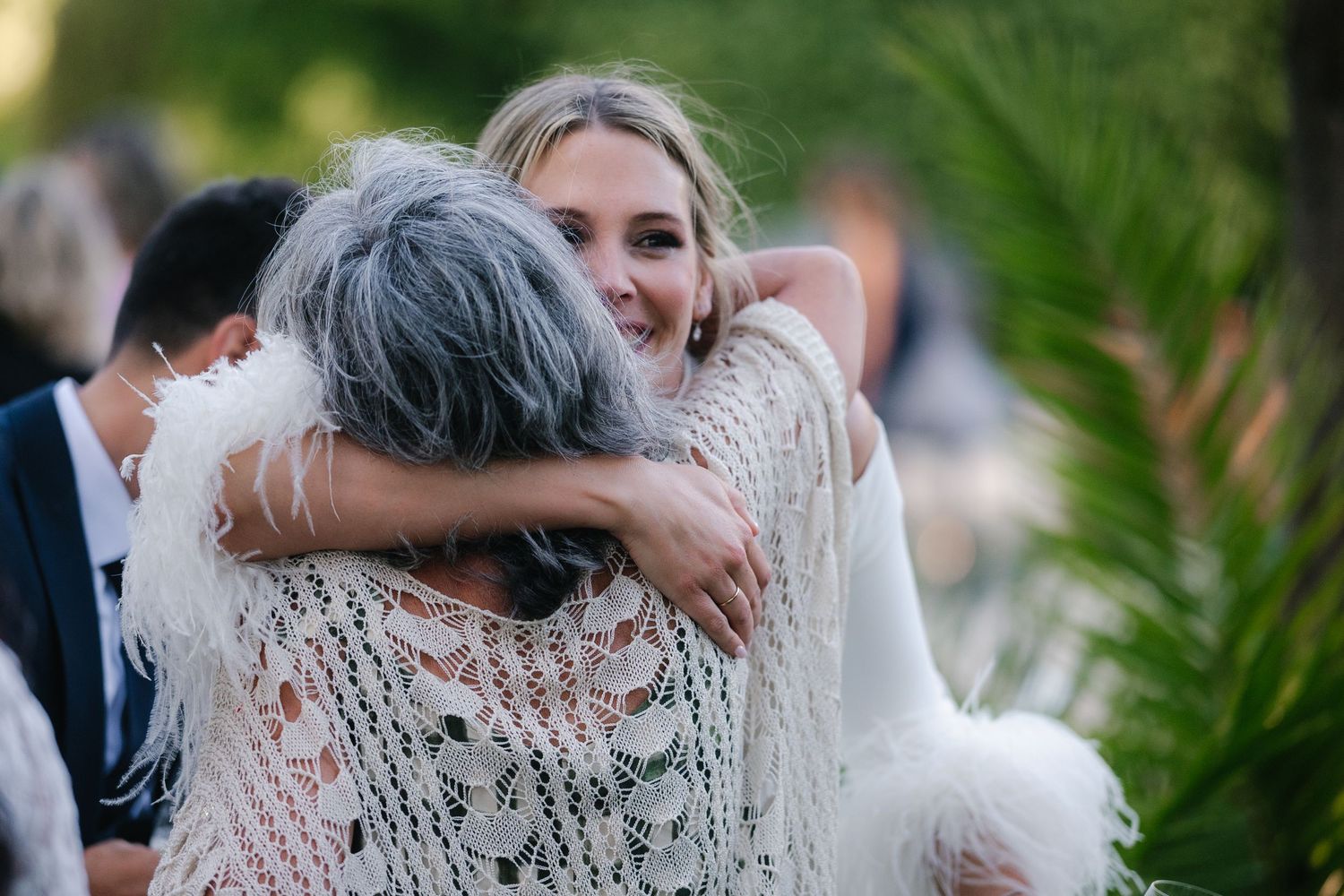 Wedding guests celebrating and dancing together during an outdoor reception with greenery in the background.