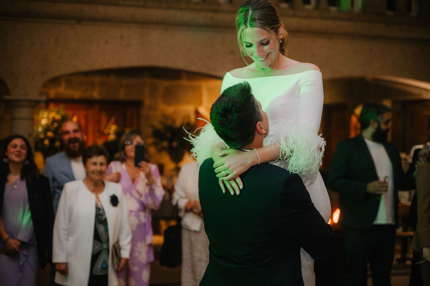Couples dancing at an elegant evening wedding reception with atmospheric green lighting.