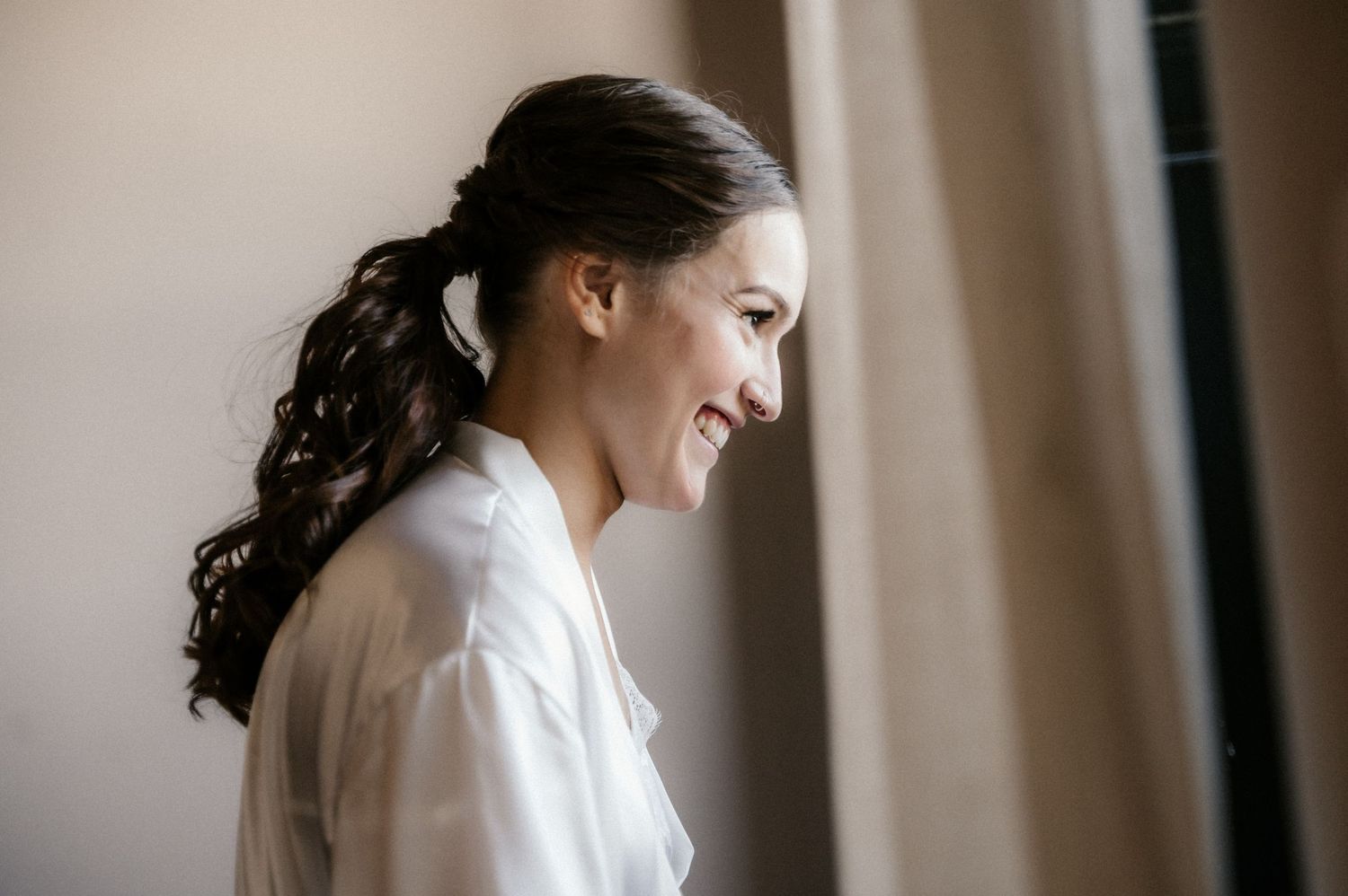 A person in a white robe getting ready in soft natural window light.