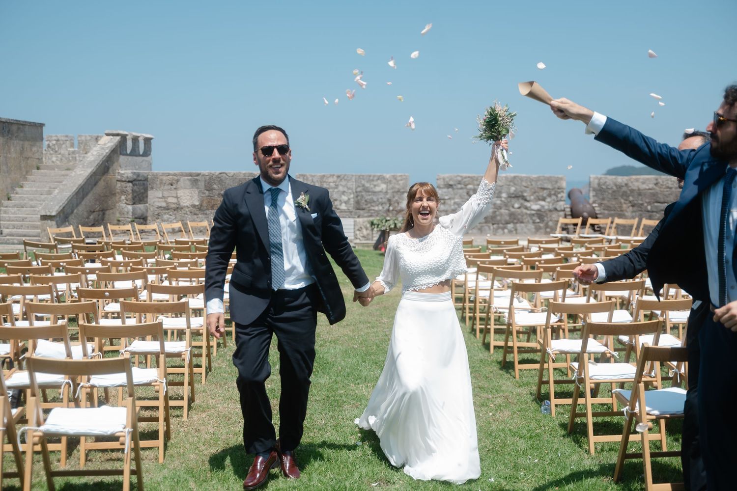 Empty wooden chairs set up on grass for an outdoor wedding ceremony with mountains in the background.
