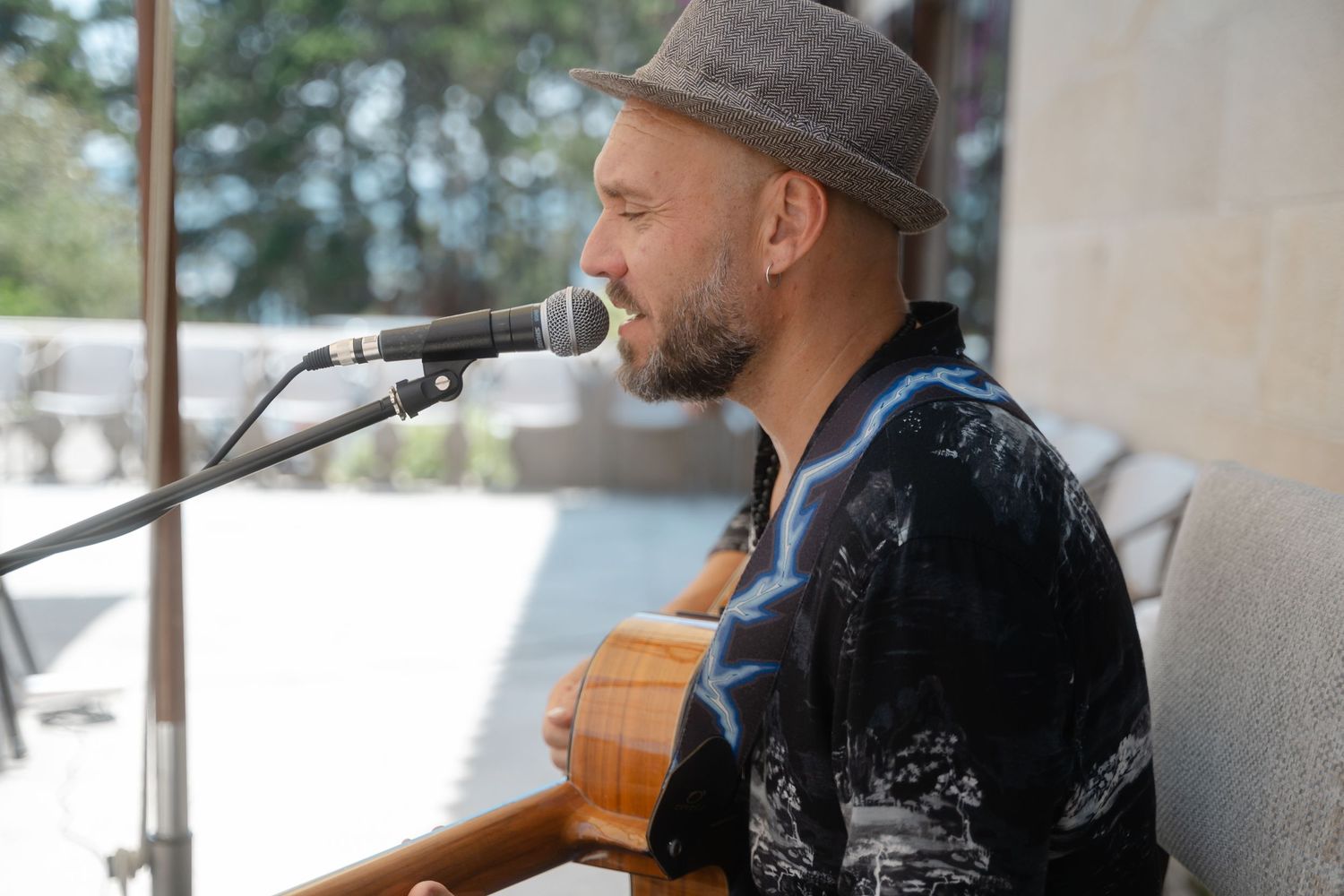 Musician performs outdoors on acoustic guitar with microphone setup and snowy winter landscape in background.