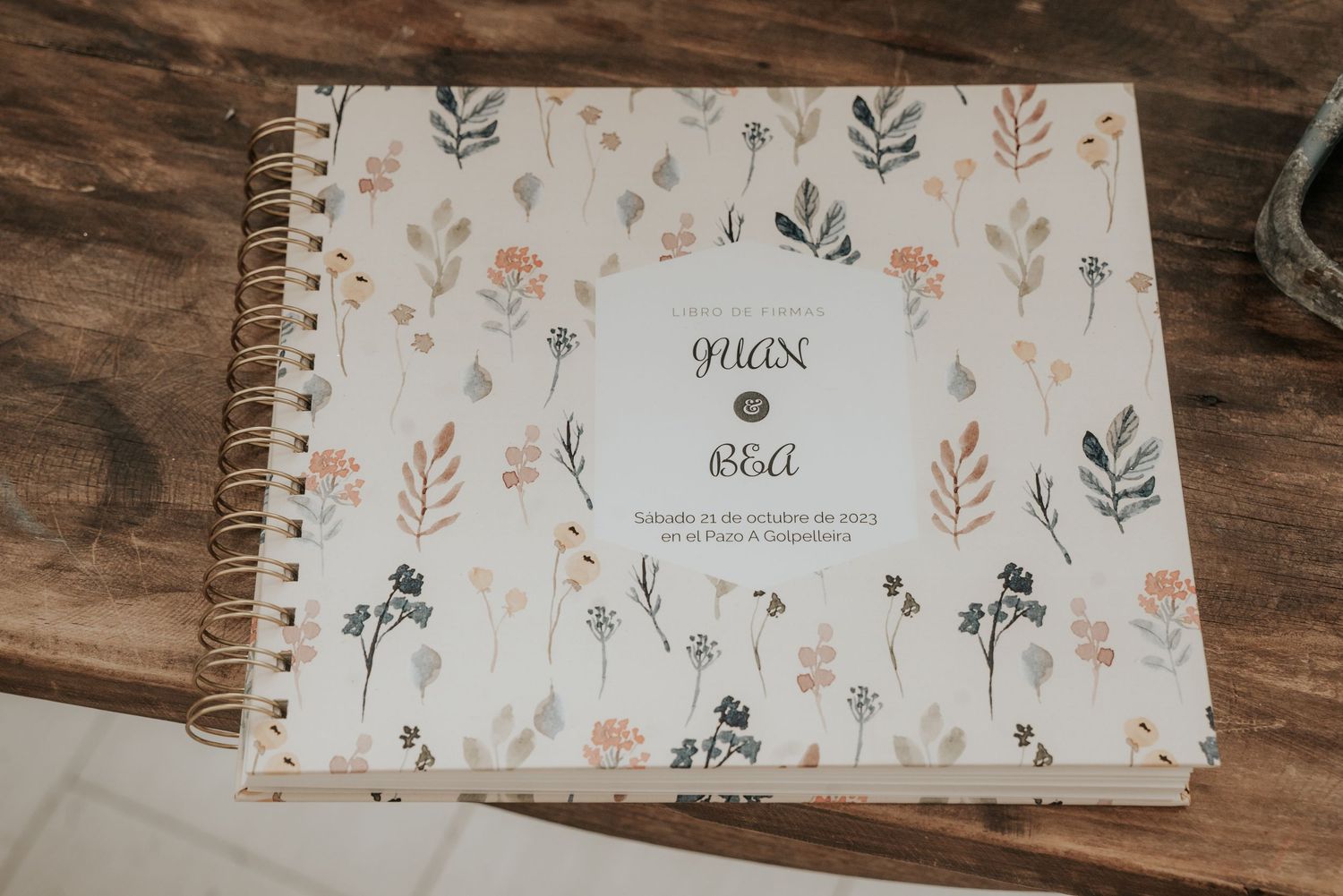 A spiral-bound notebook with delicate floral pattern cover featuring pink and green botanical illustrations on white background.