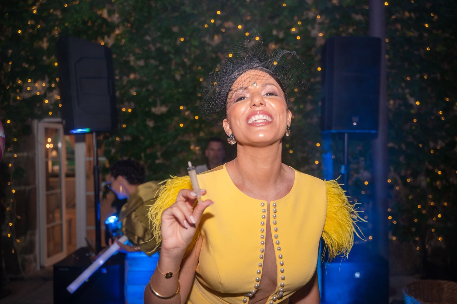 Person in a yellow dress dancing joyfully under party lights and falling confetti.