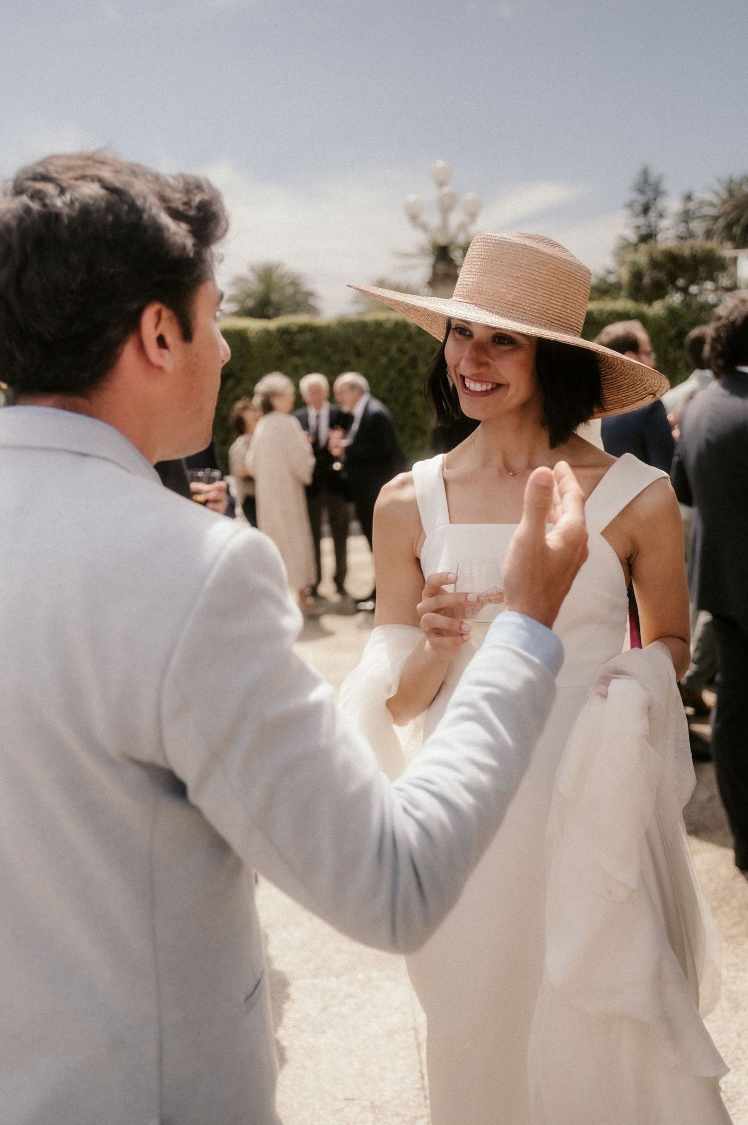 A series of candid wedding photos showing a couple sharing joyful moments in white attire and a sun hat outdoors.
