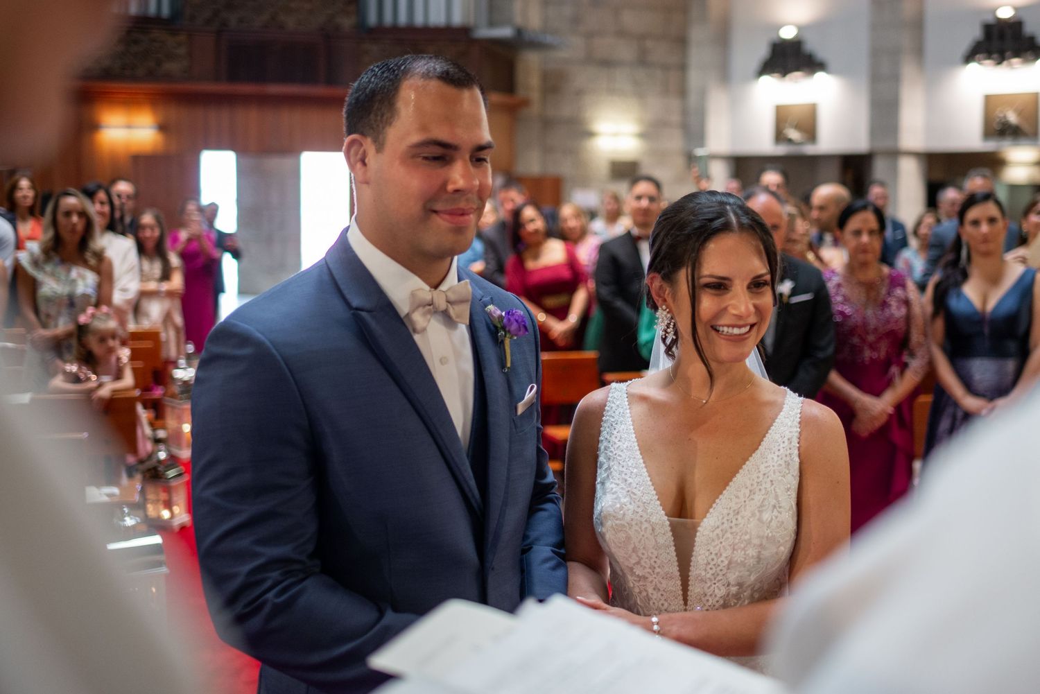 A bride and groom share a joyful moment during their wedding reception surrounded by guests.