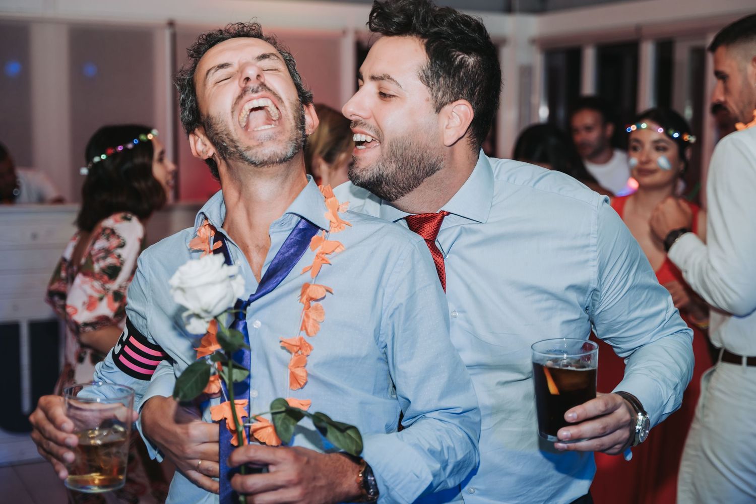 Party guests celebrating and having fun with drinks on the dance floor at a wedding reception.
