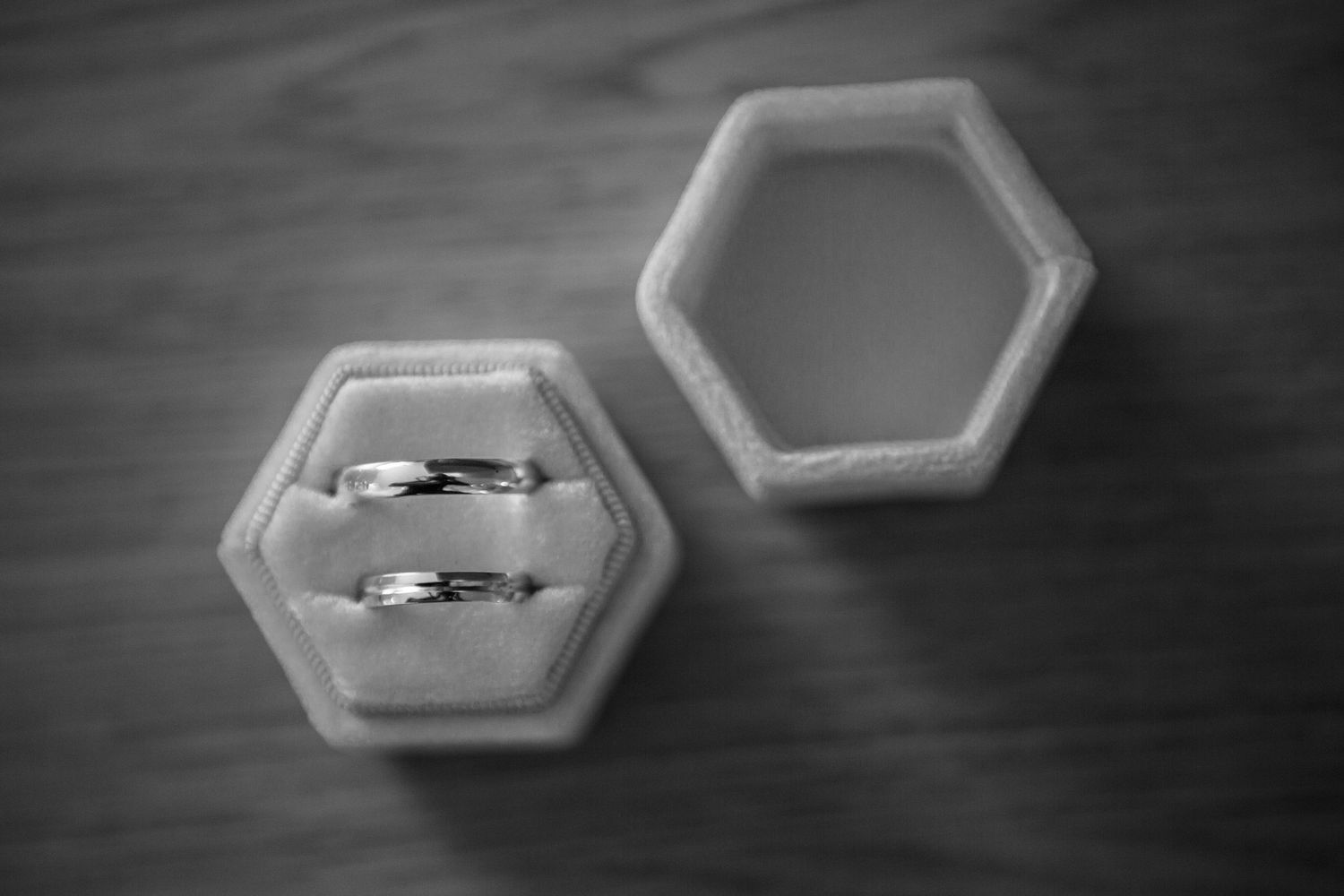 Wedding rings displayed on hexagonal surfaces in black and white.