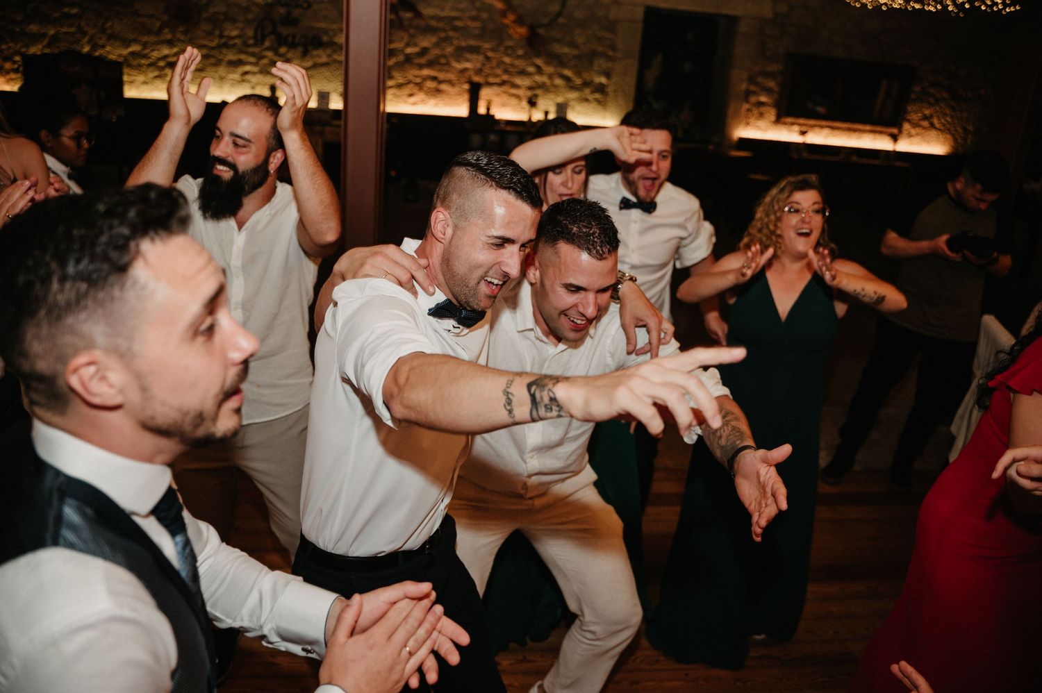 People dancing and celebrating energetically at a dimly lit party venue.