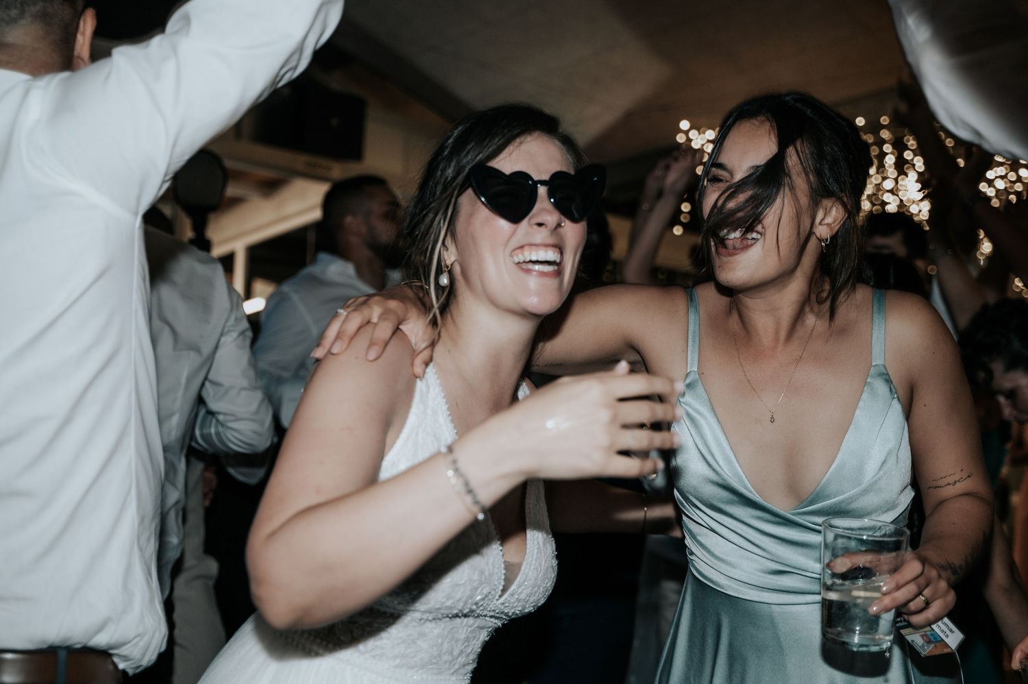 A group of wedding guests dance and celebrate together on the dance floor during a reception celebration.