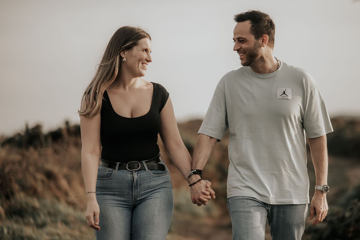 Candid lifestyle photos of a couple walking and laughing together outdoors in casual attire.