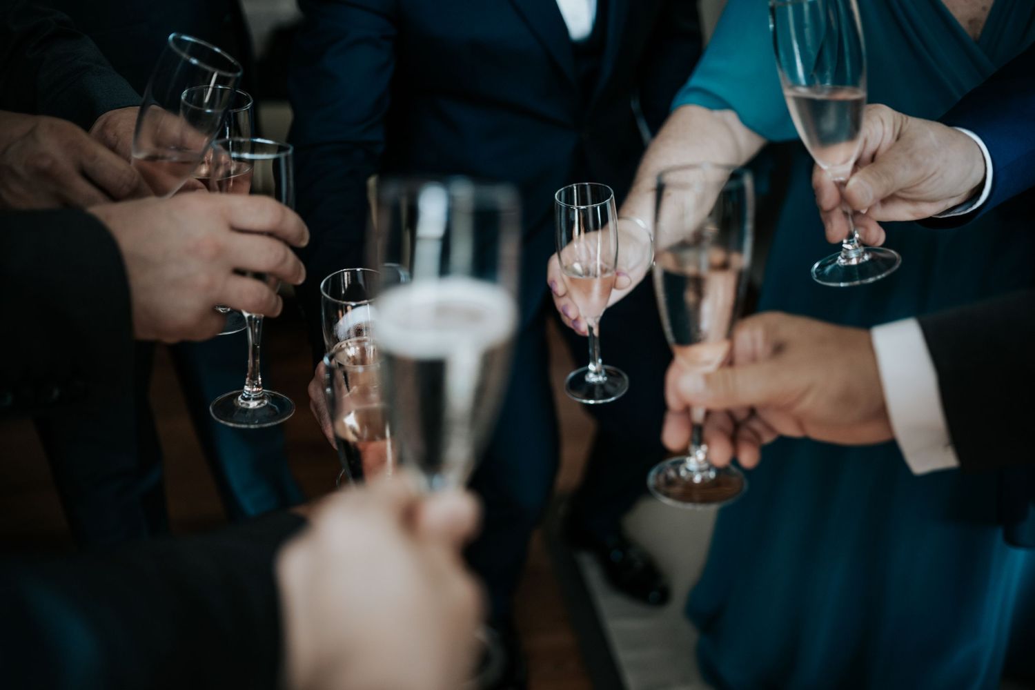 Several hands raise champagne glasses in a celebratory toast at a formal gathering.