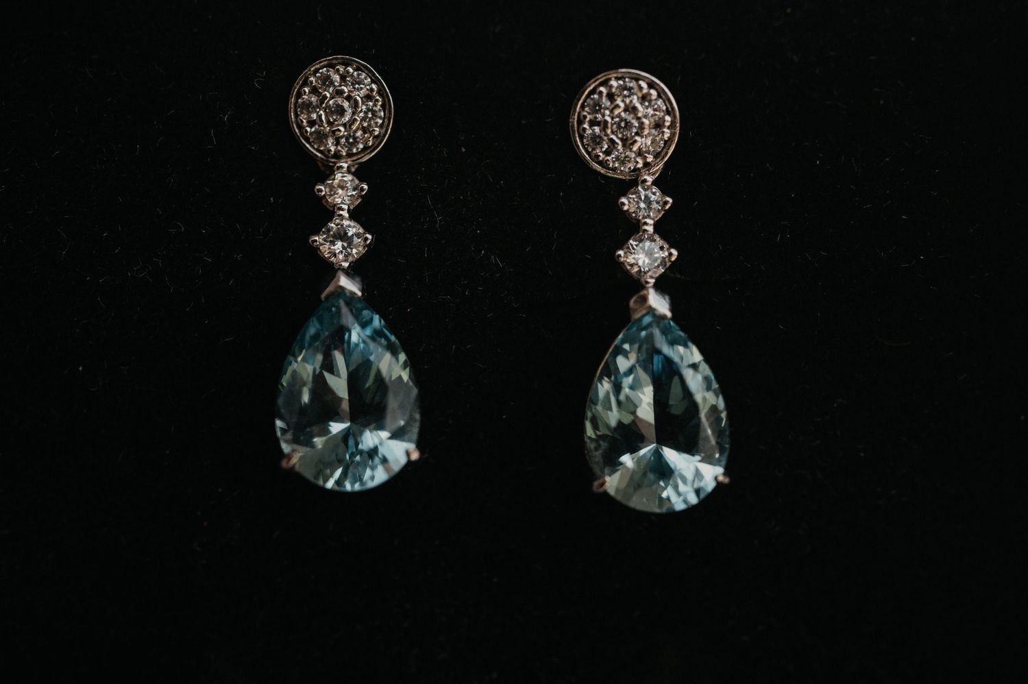 Elegant silver and gemstone drop earrings displayed in a row against a black background.