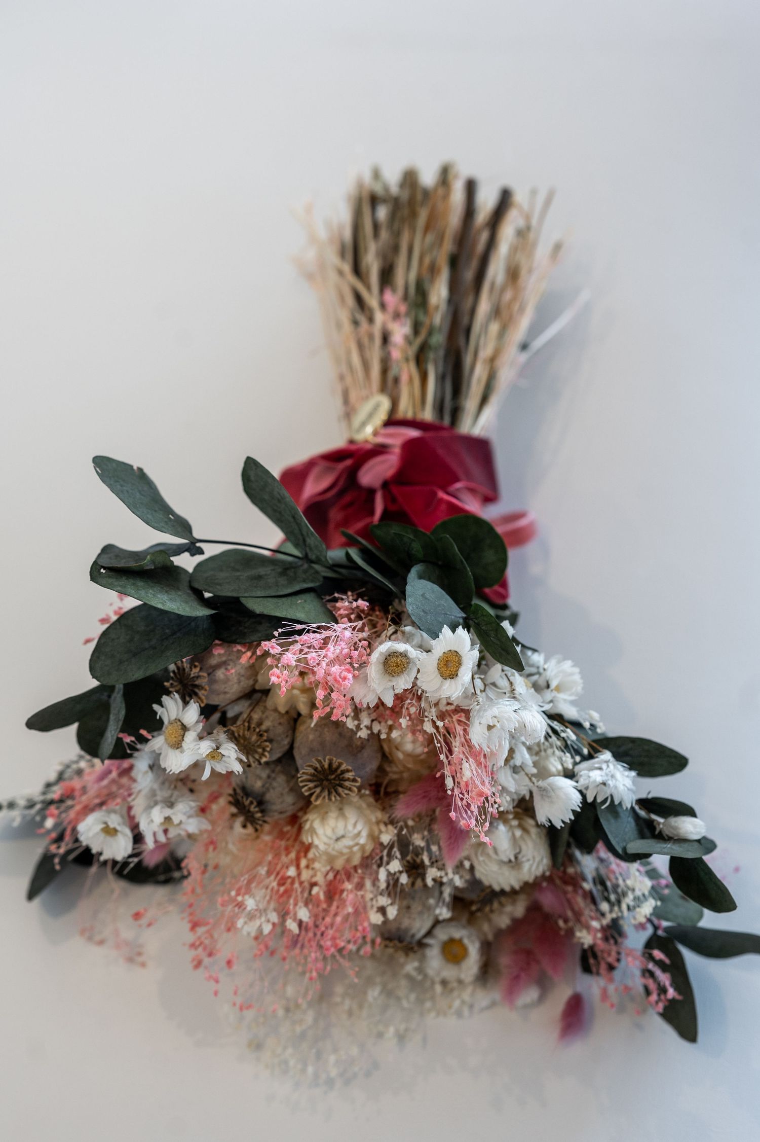 A series of floral arrangements featuring dried roses, daisies, and eucalyptus leaves in varying stages of assembly.