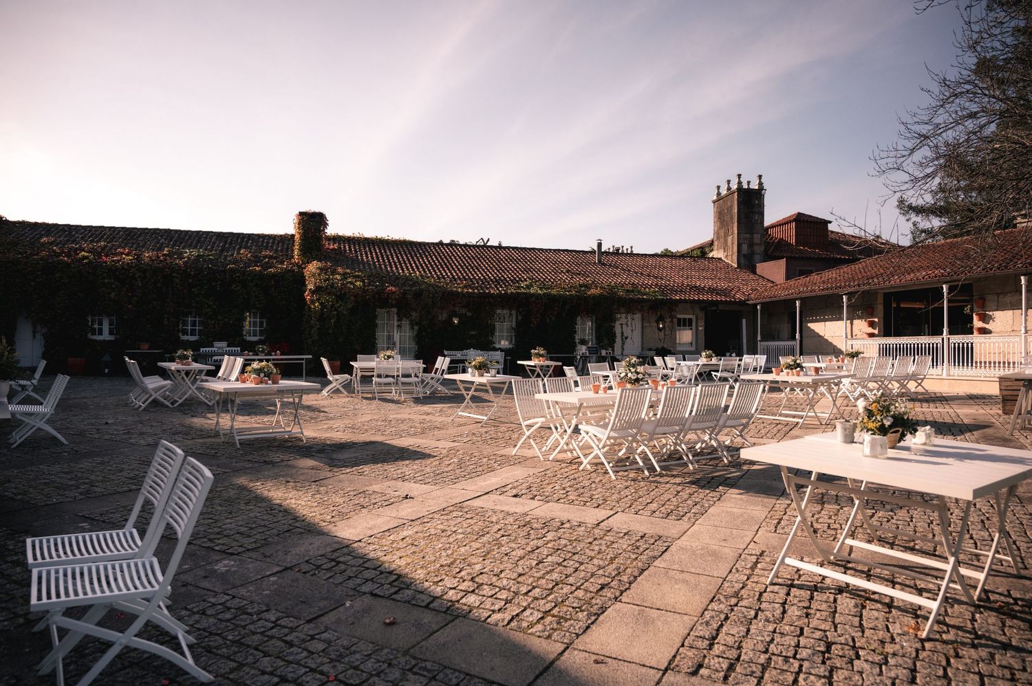White folding chairs arranged in rows on a sandy beach for an outdoor wedding ceremony at sunset.