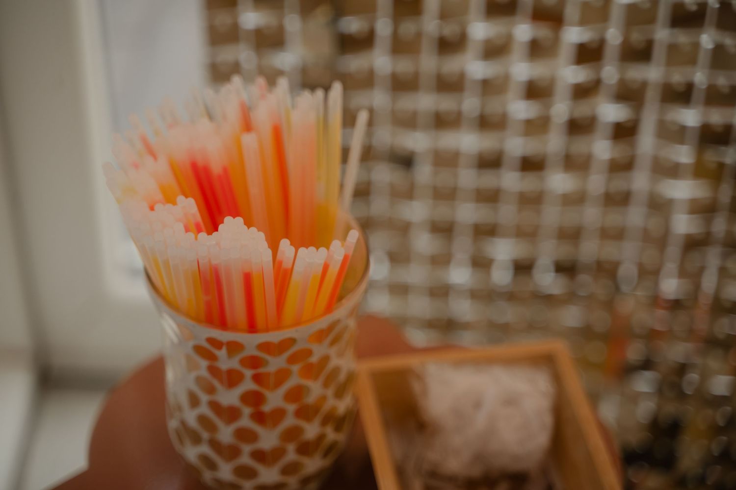 Orange and white striped straws displayed in a decorative holder against a patterned background.