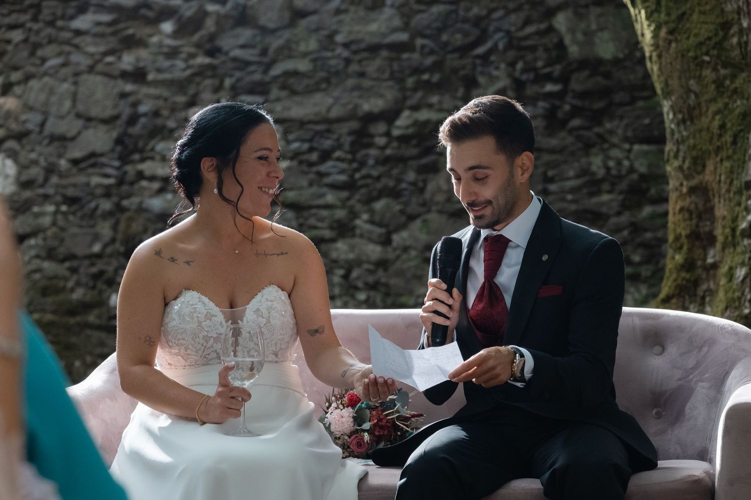 Intimate wedding ceremony moment against a rustic stone wall backdrop.