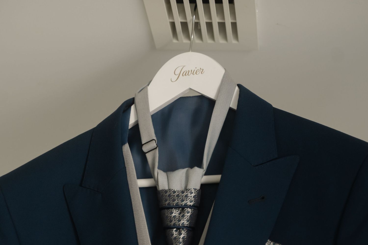 A row of dark blue and navy suit jackets hanging on wooden hangers in a retail clothing store display.