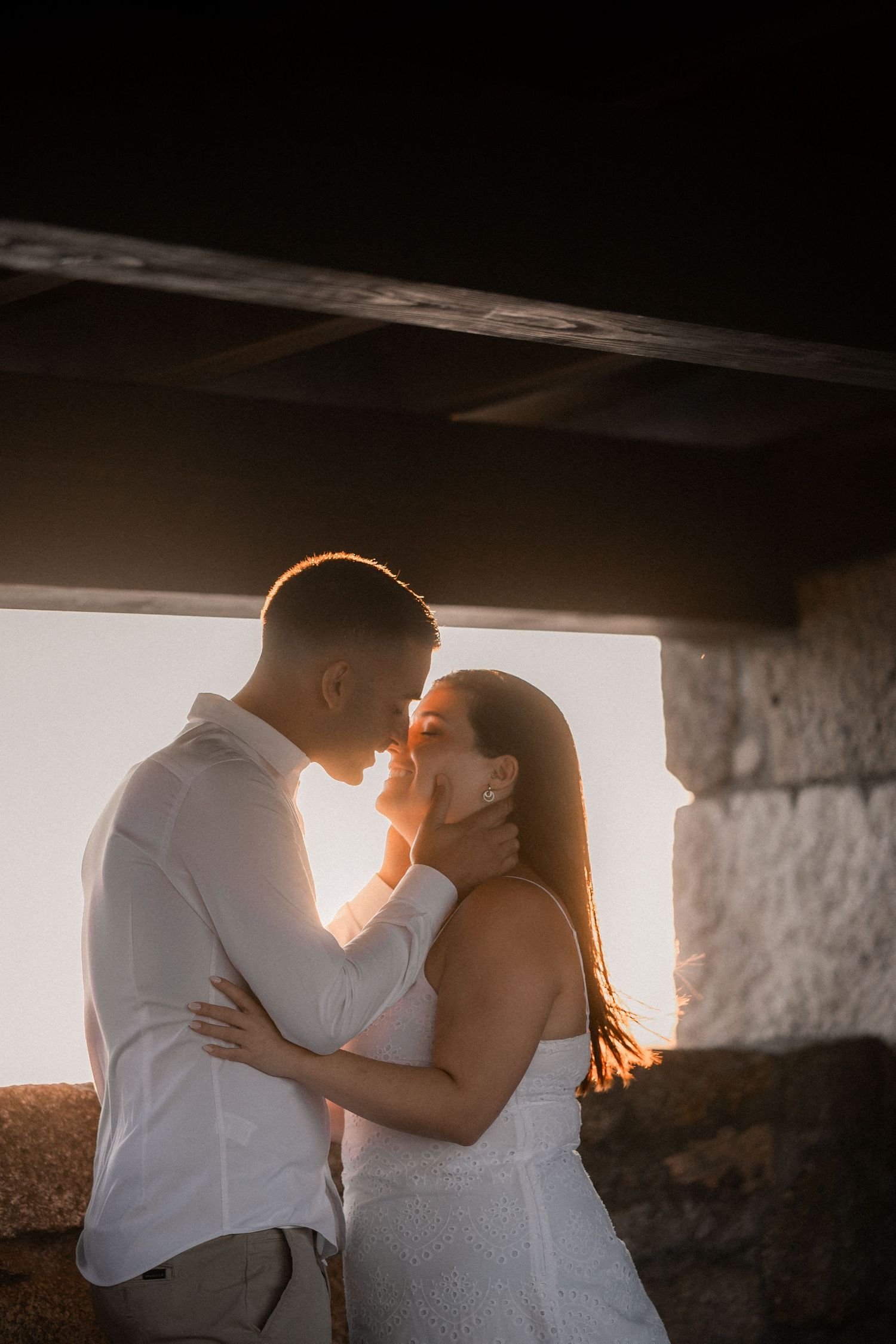 Romantic silhouettes against sunset light through a rustic window frame.