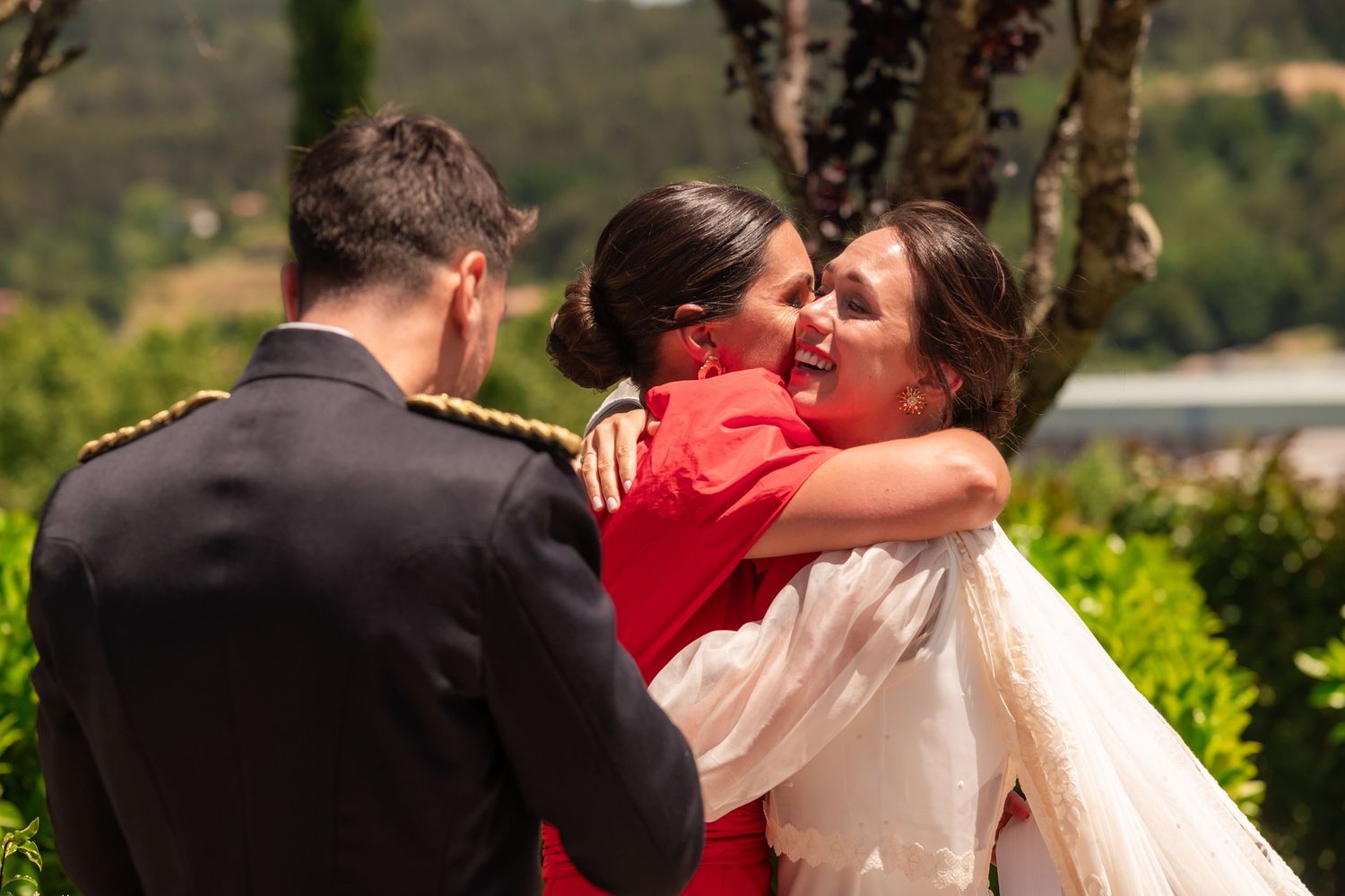 A couple shares a romantic kiss in an outdoor garden setting with lush greenery in the background.
