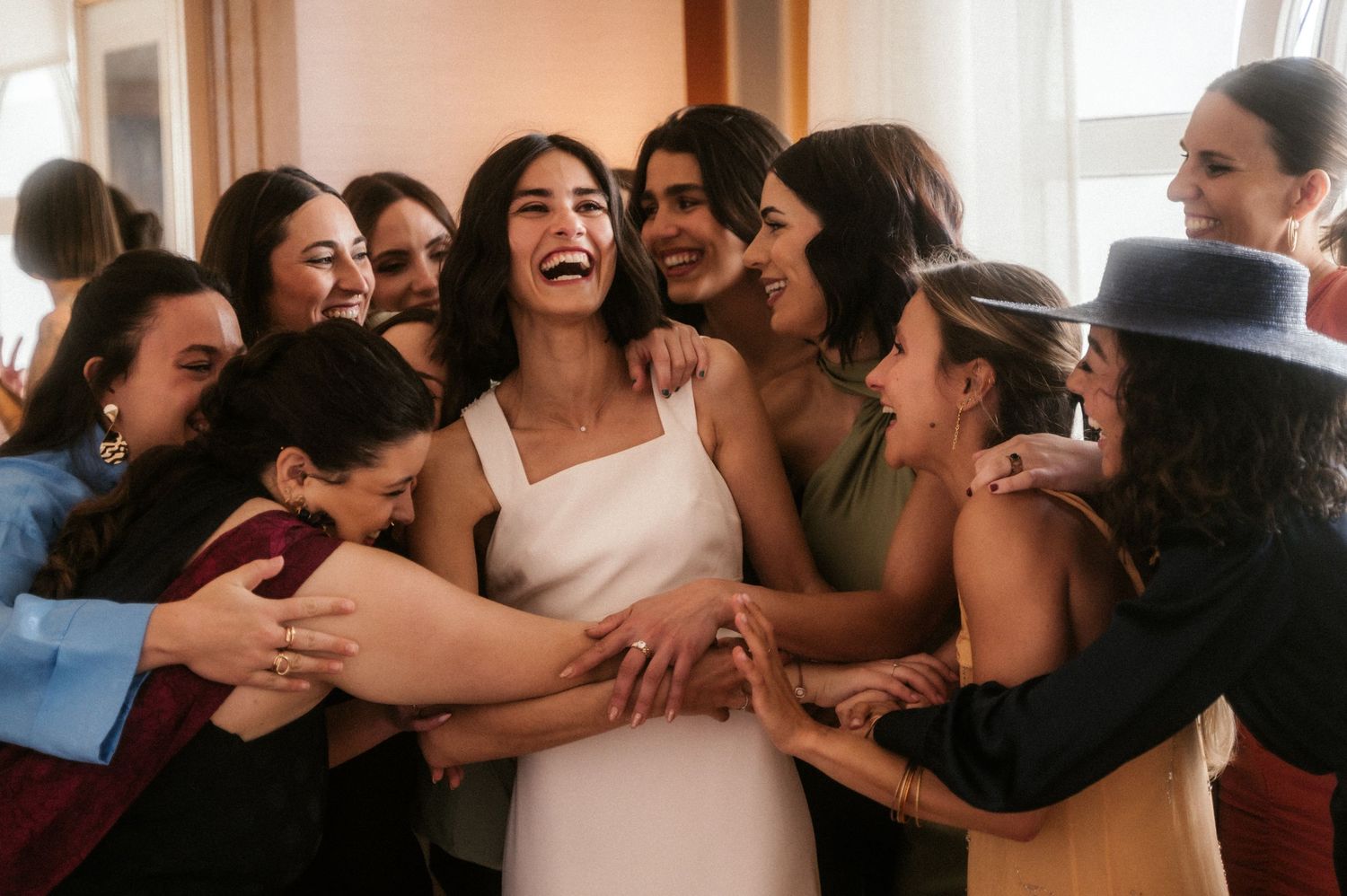 A group of people laugh and embrace joyfully at what appears to be a social gathering or celebration.