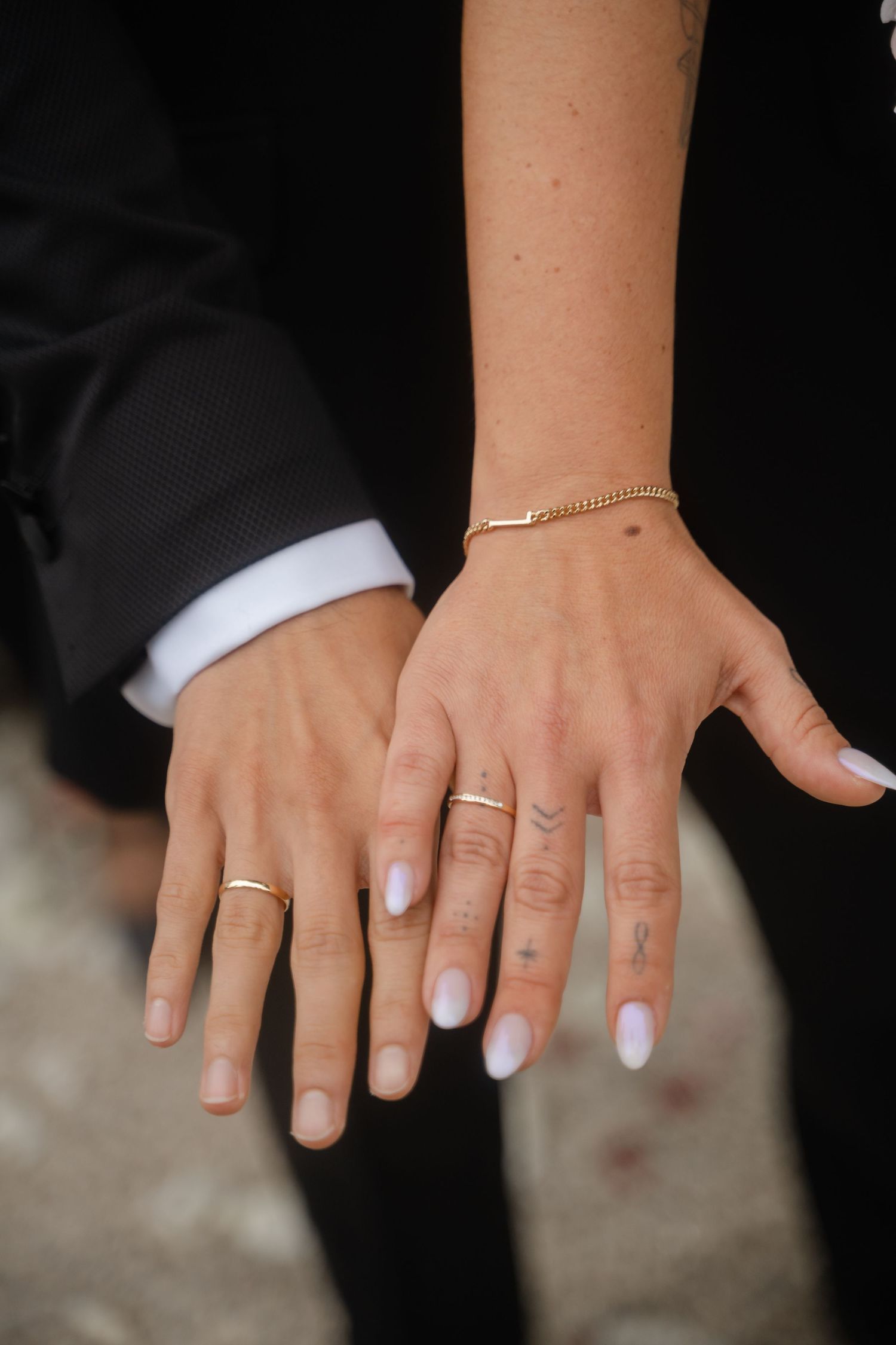 A sequence of hands showing wedding rings and manicured nails against a dark background.