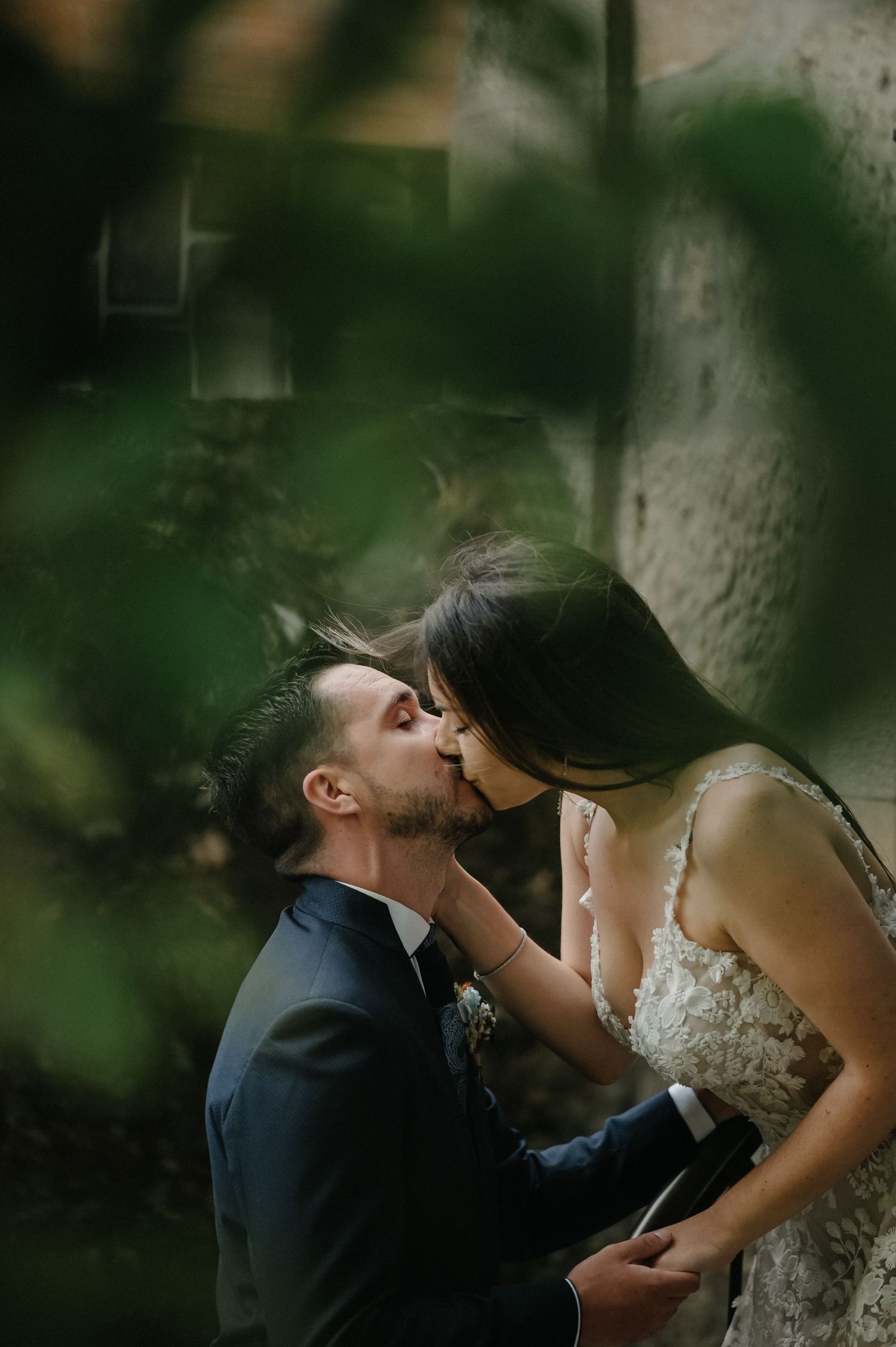 Romantic couple shares an intimate moment against a tree trunk in a dreamy forest setting.