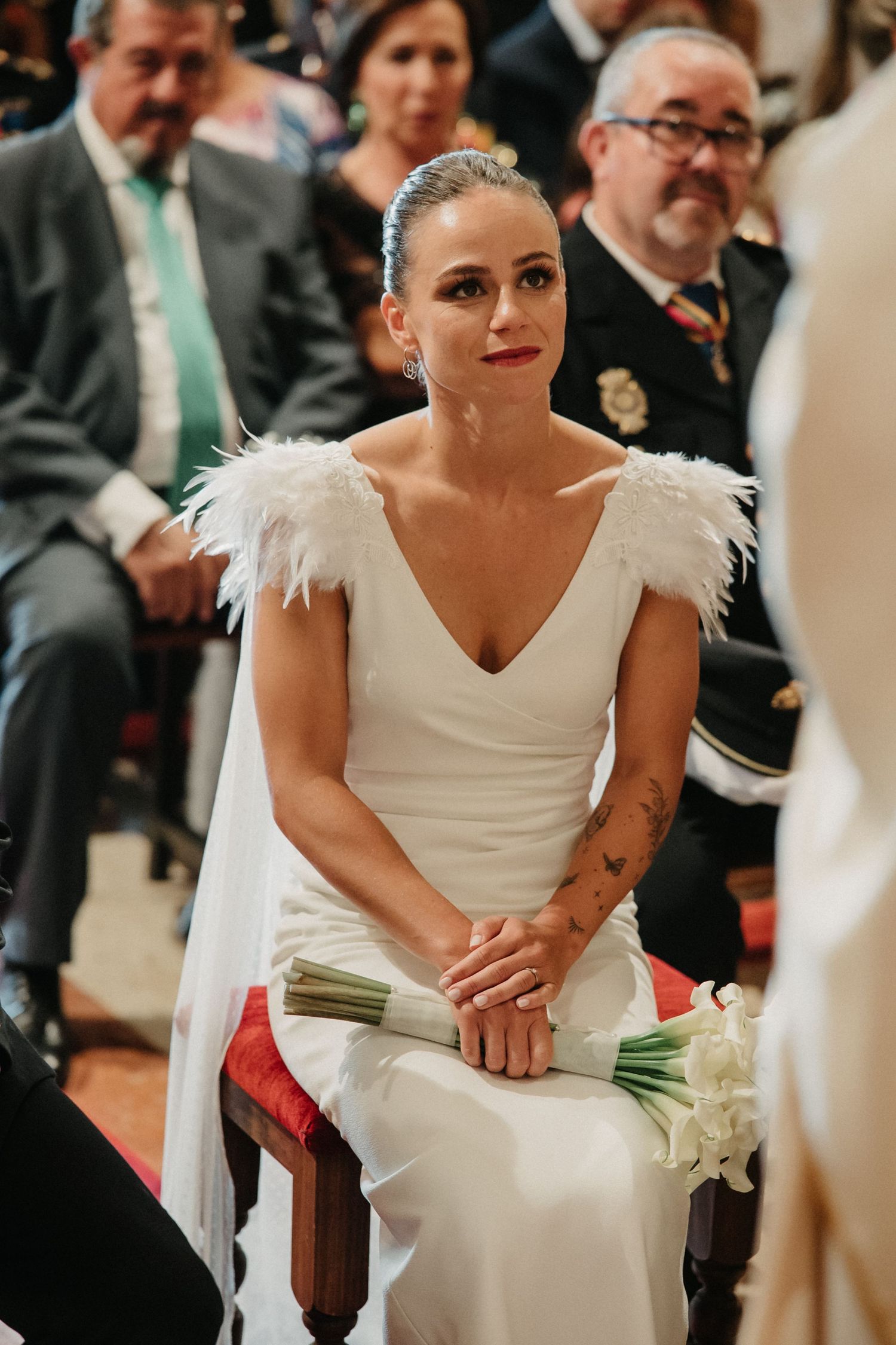 Wedding guests watching attentively during an emotional indoor ceremony with white decor.