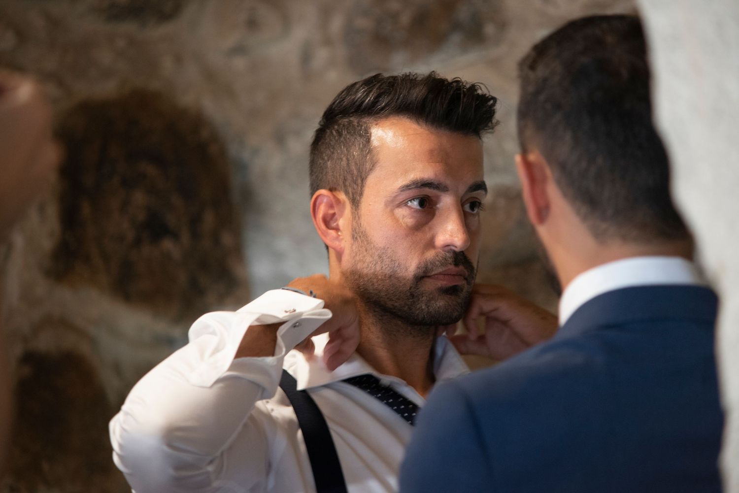 Two men in formal suits having an intimate conversation at a wedding celebration.