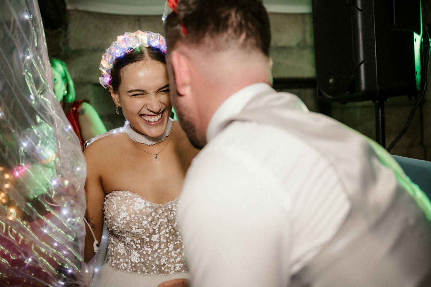 A joyful moment captured between a bride in a sparkly strapless gown and another person during a wedding celebration.