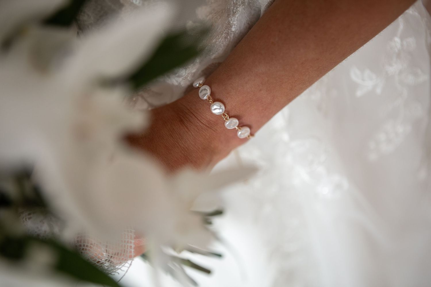 Close-up of delicate bridal jewelry and dress details.