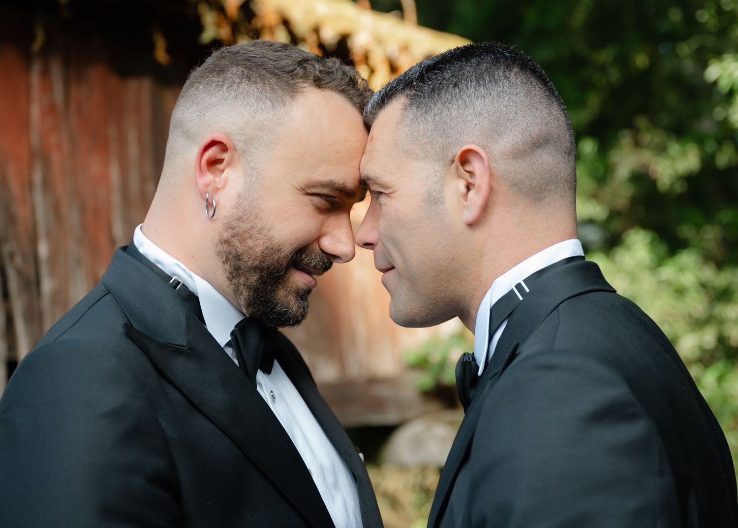 Two grooms in black tuxedos share a tender moment during their wedding celebration.Wedding photographer Spain. Galicia.