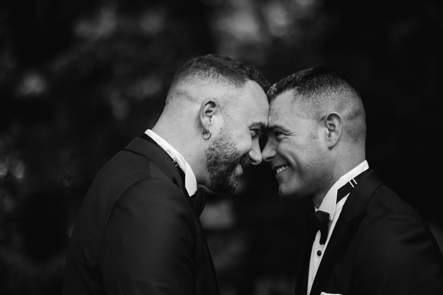 A couple shares a tender moment during their wedding ceremony in a black and white photograph.