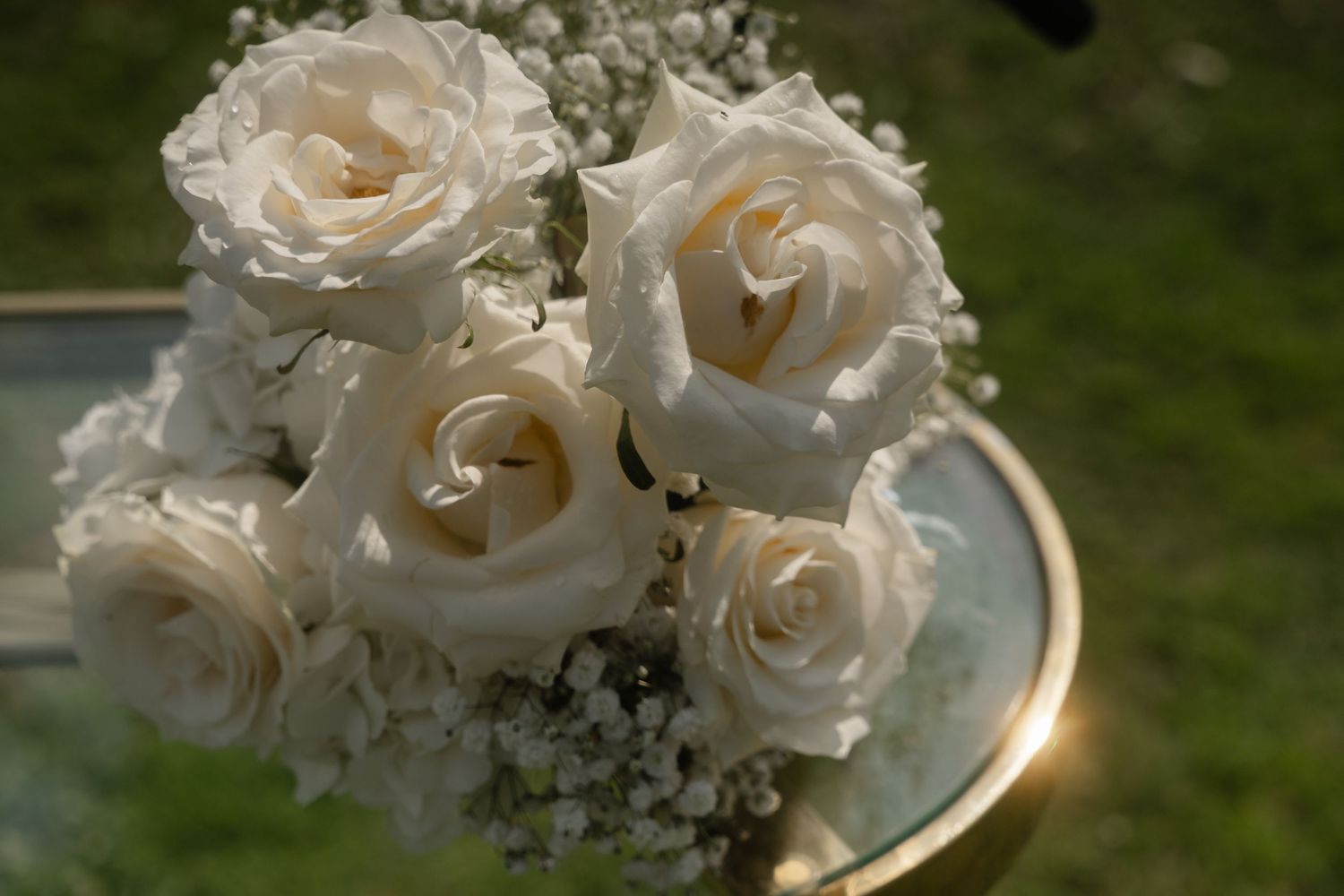 A collection of white roses and baby's breath flowers arranged in elegant wedding bouquets against a green background.